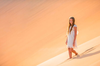 Portrait of girl walking on sand dunes at desert