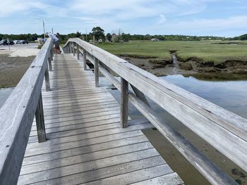 Wooden boardwalk leading towards water against sky