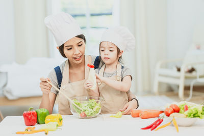 Happy friends preparing food in kitchen