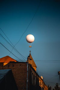 Low angle view of balloons against buildings at dusk