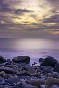 Rocks on beach against sky during sunset