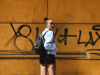 Portrait of teenage boy wearing sunglasses standing against wall