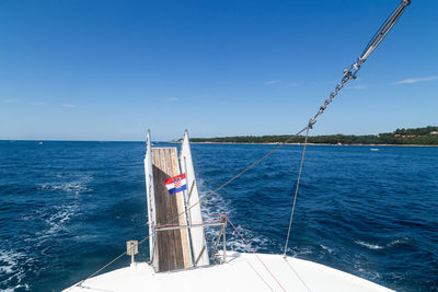 Sailboat sailing in sea against blue sky