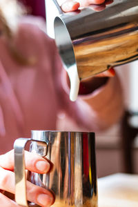 Close-up of hand pouring coffee cup
