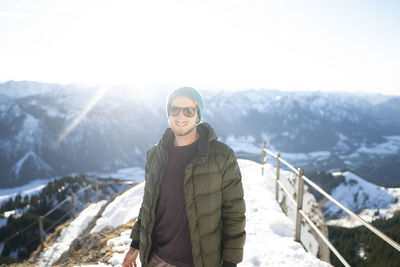 Portrait of young woman standing on snowcapped mountains during winter