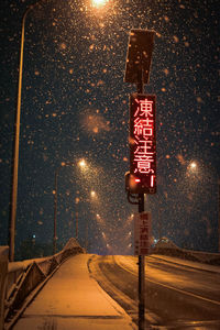 Road sign on snow covered street at night