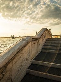 View of old building by sea against cloudy sky