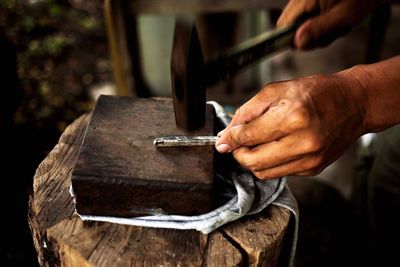 Cropped hand hammering on metal in workshop