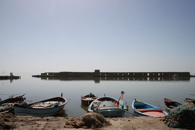 Boats moored in sea against clear sky