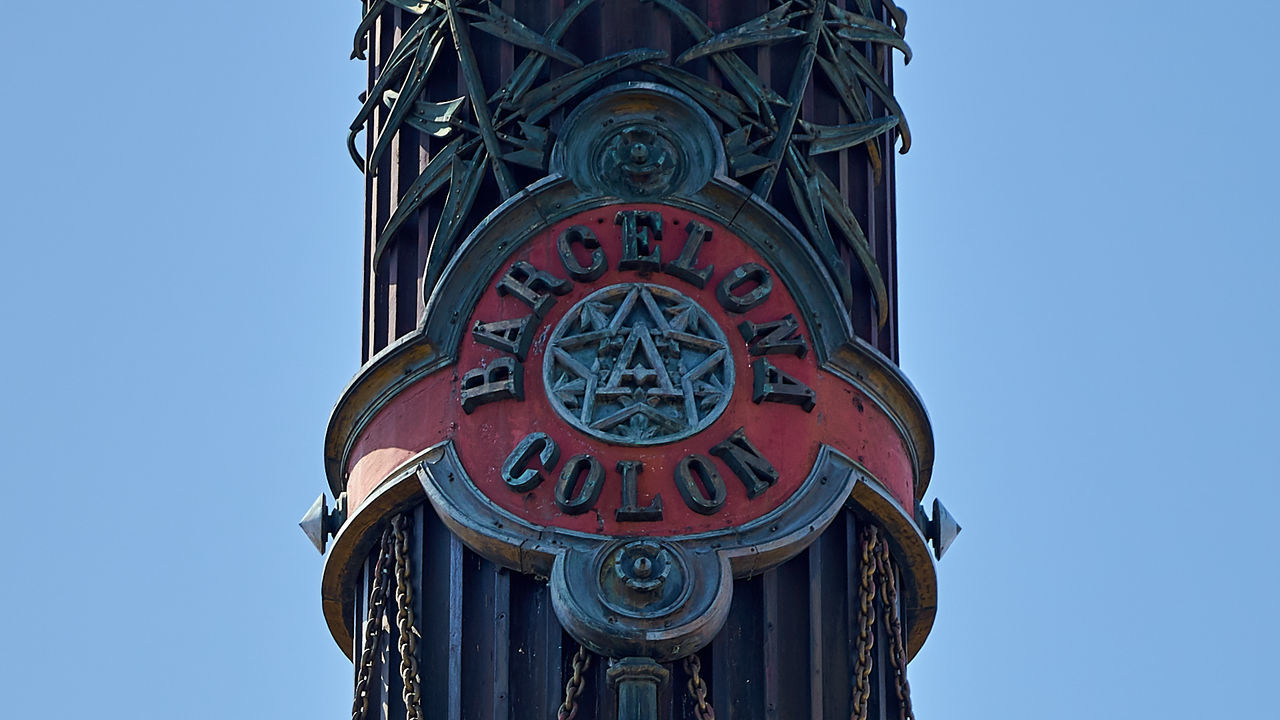 LOW ANGLE VIEW OF CLOCK TOWER AMIDST BUILDINGS AGAINST CLEAR BLUE SKY