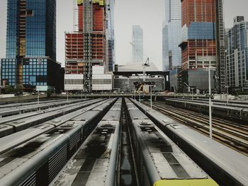 Railroad tracks amidst buildings in city against sky