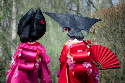 Rear view of women wearing kimono walking in forest