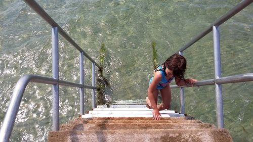 High angle view of girl climbing steps in sea