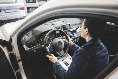 High angle view of senior woman examining while sitting in car