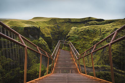 Footbridge over mountain against sky