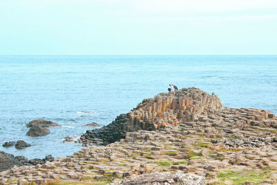 Rock formations on shore against sky