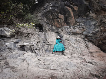 Full length of woman sitting on rock