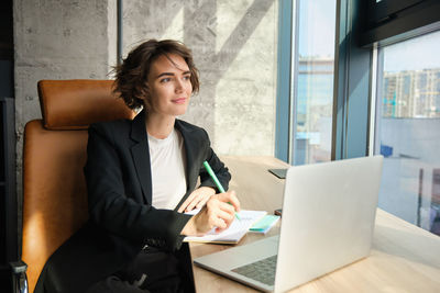 Portrait of young woman using digital tablet while sitting in office
