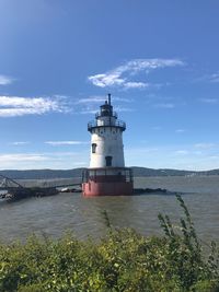 Lighthouse by sea against sky