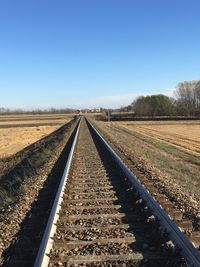 Railroad tracks against clear blue sky