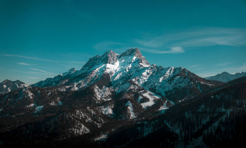 Aerial view of snowcapped mountains against blue sky