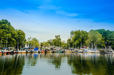 Boats moored in lake against blue sky