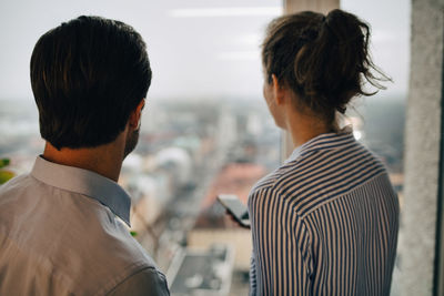 Rear view of business colleagues looking through window at creative office