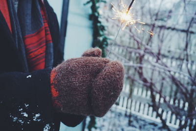 Midsection of person holding sparkler during winter
