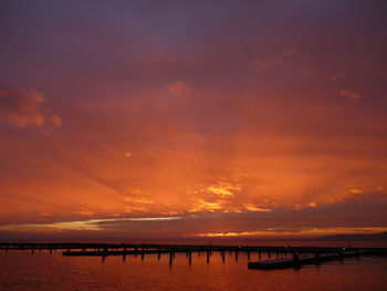 Silhouette pier over sea against sky during sunset