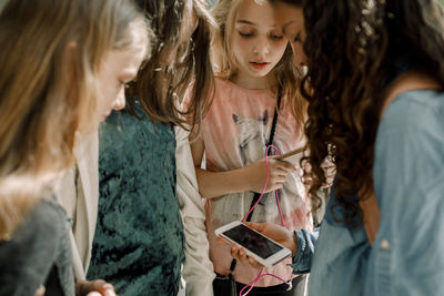 Female students looking at phone while standing in school corridor