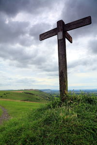 Cross on field against sky