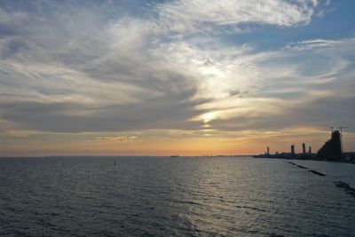 Scenic view of sea against cloudy sky during sunset