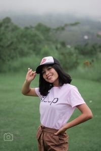 Portrait of a smiling young woman standing on field