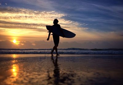 Silhouette of people on beach at sunset