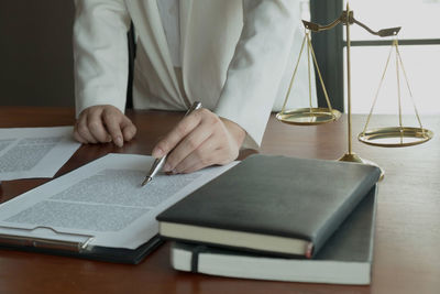 Midsection of man reading book on table