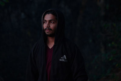 Portrait of man standing against black background