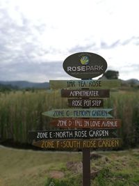 Close-up of road sign on field against sky