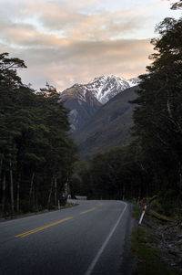 Road amidst trees and mountains against sky