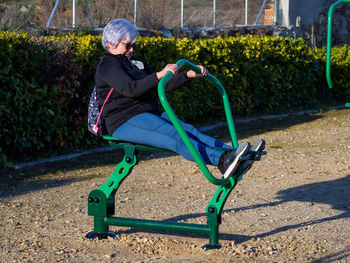 Full length of senior woman exercising at playground