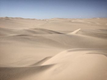 Sand dunes in desert against clear sky