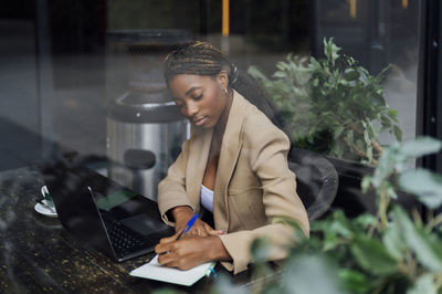 Young businesswoman making notes at cafeteria