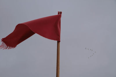 Low angle view of red flag against sky