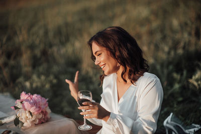 Young woman drinking water from glass while standing outdoors