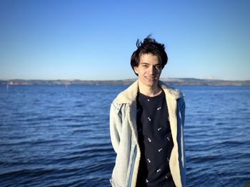 Portrait of man standing by sea against clear sky