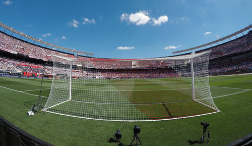 People playing soccer on field against sky