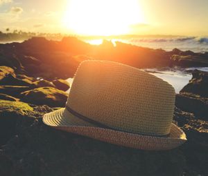 Close-up of hat against sea during sunset