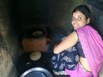 Smiling woman cooking chapatti at kitchen