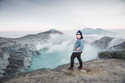 Full length of woman standing on mountain against sky