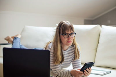 Young woman using mobile phone at home