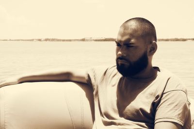 Portrait of young man at beach against sky